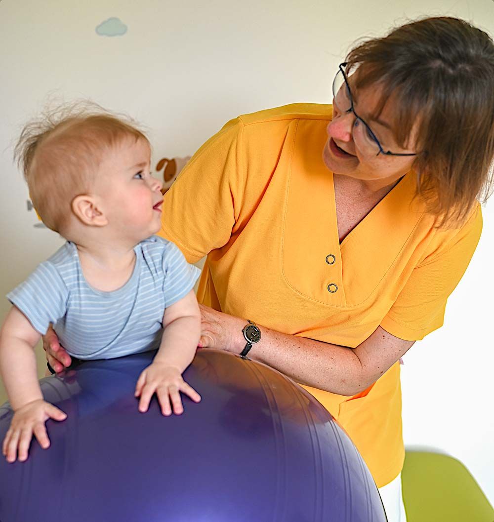 Kind und Therapeutin an einem Sitzball